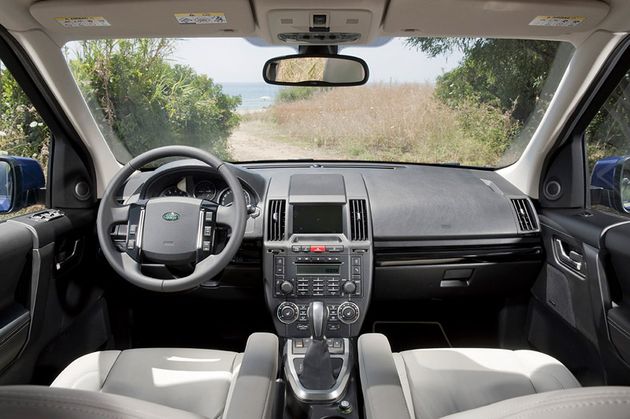 Довольно аскетичный салон рестайлингового LR Freelander изменился мало - появилась новая отделка передней панели, а также новые цветовые комбинации обивки сидений и дверных панелей. Пластик передней панели - прочный, местами жесткий, но чаще приятный на ощупь. Алюминиевые полоски на руле - это "бибикалки". Слева - кнопки управления круиз-контролем, справа - музыкой